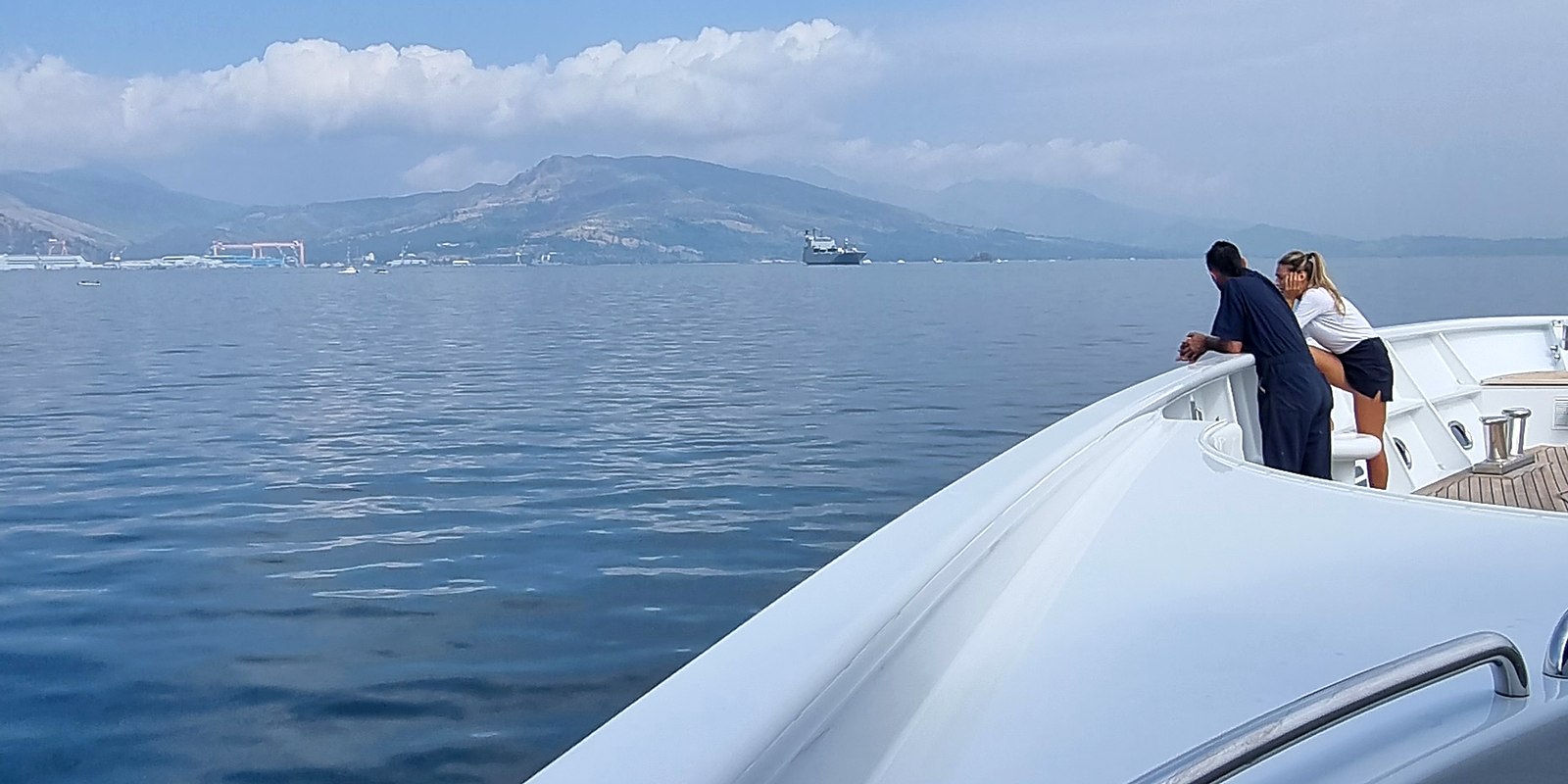 Two crew members leaning on the bow rail, looking out at the horizon