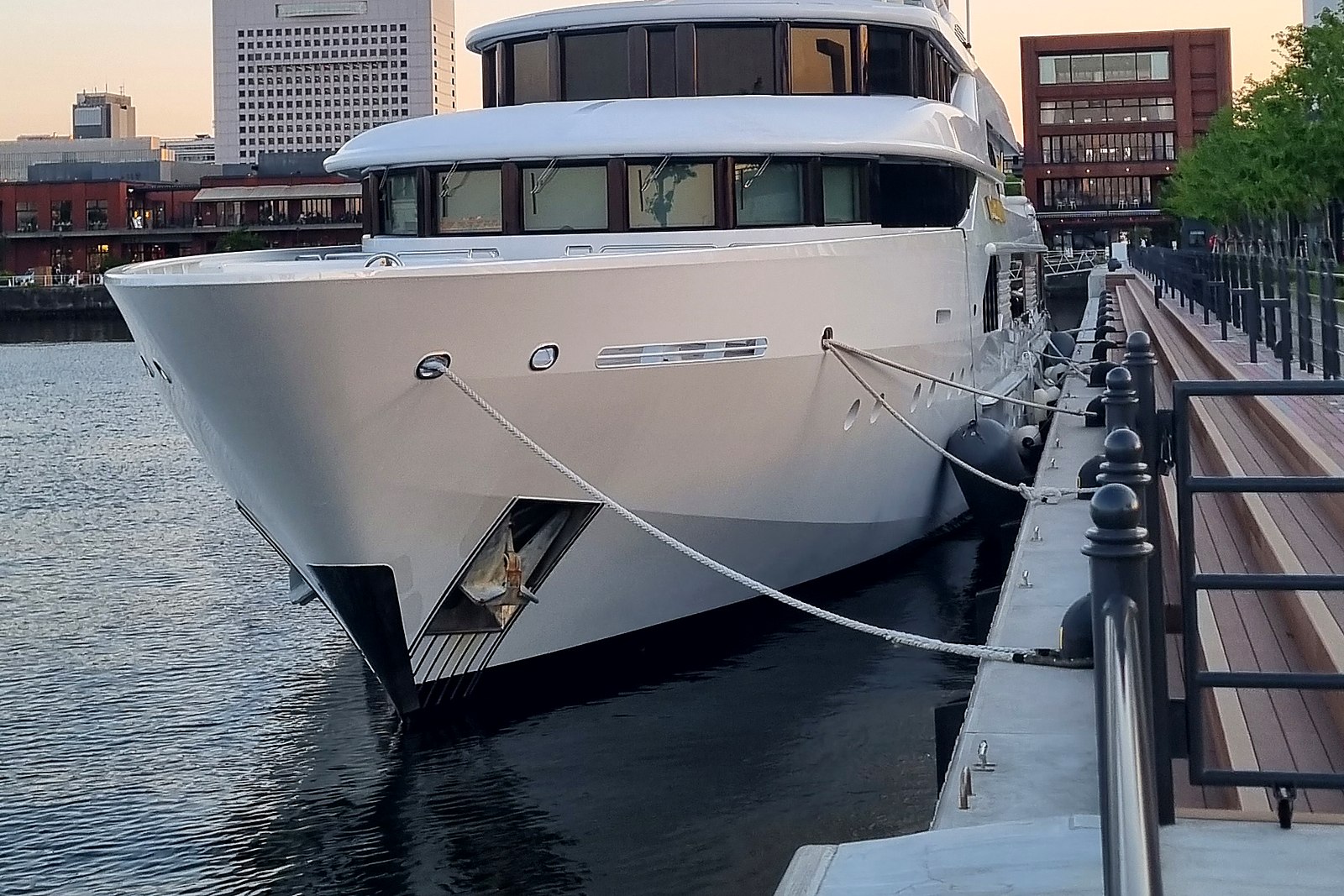 Superyacht bow moored at a city marina at dusk