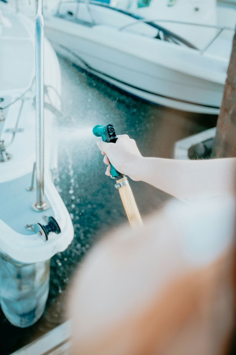 Crew member washing down a yacht with a hose