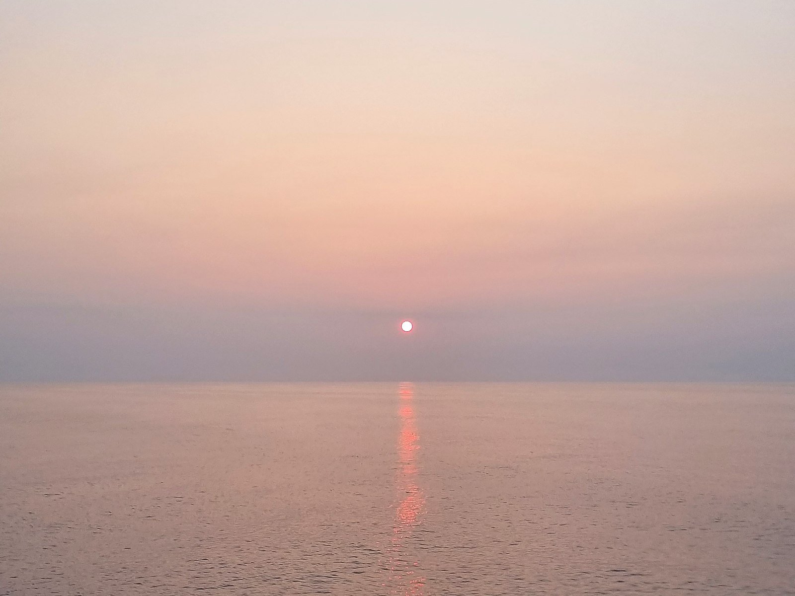 Sunrise over calm open water, seen from a superyacht underway