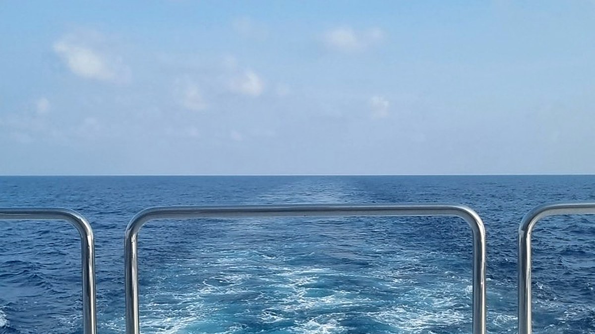 View over the stern railing across open blue water